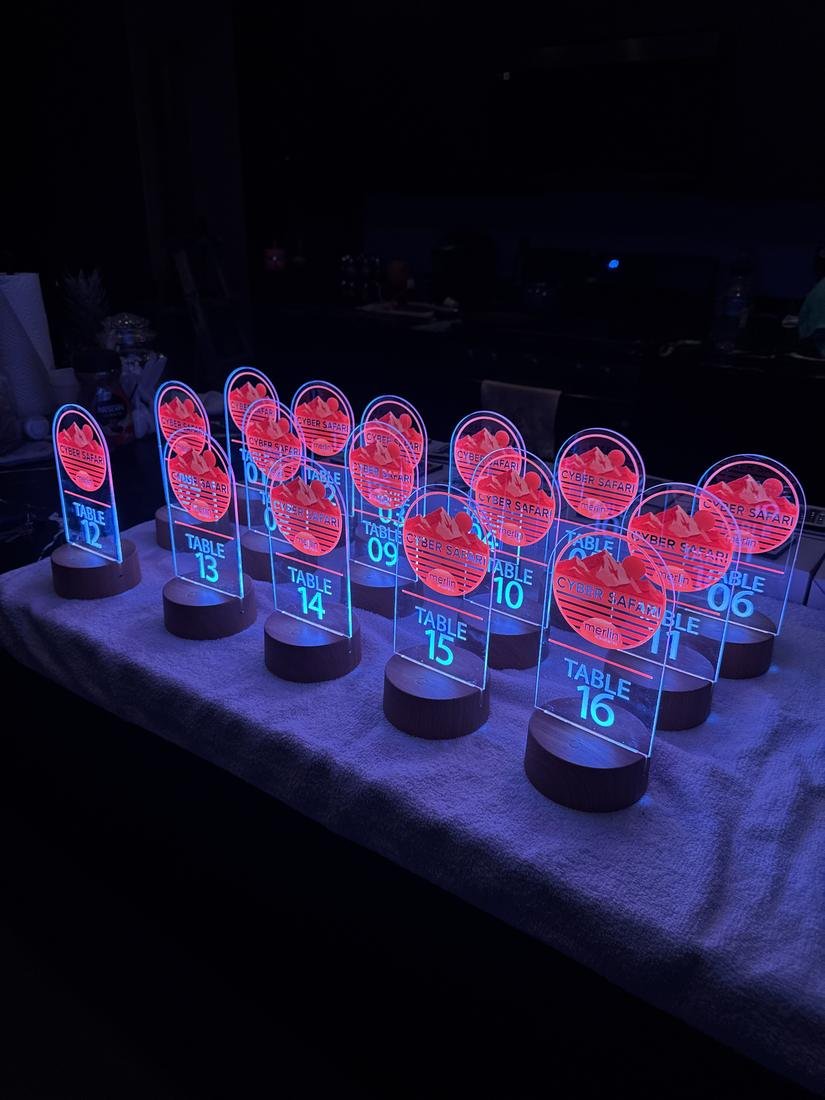 Arched acrylic table numbers with a printed logo, glowing on lit wooden bases