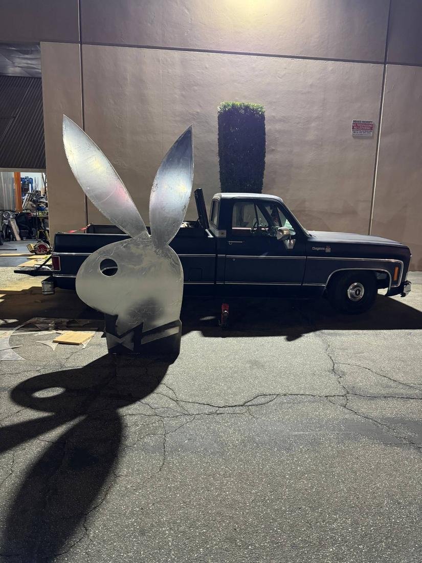 Large fabricated metal bunny head piece standing outside the shop next to a pickup truck